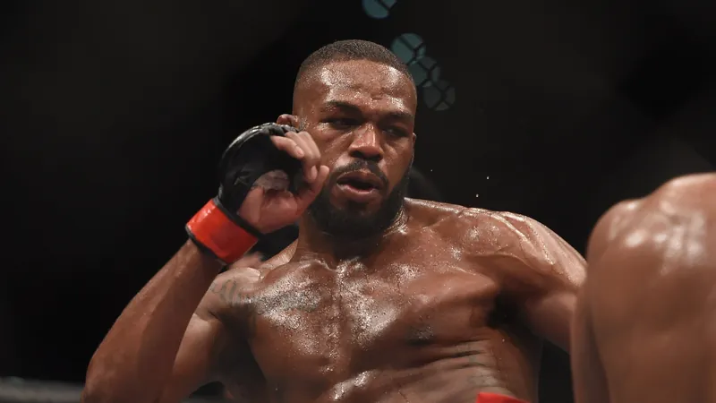 Jon Jones kicks Daniel Cormier at UFC 182 with his right glove guarding his chin